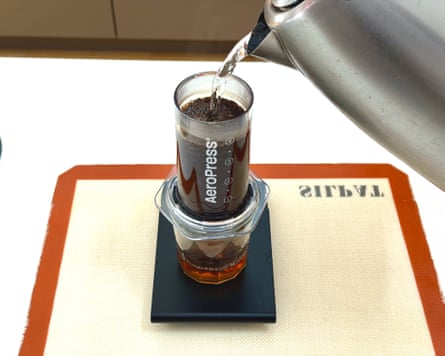 A person making coffee with an aeropress clear