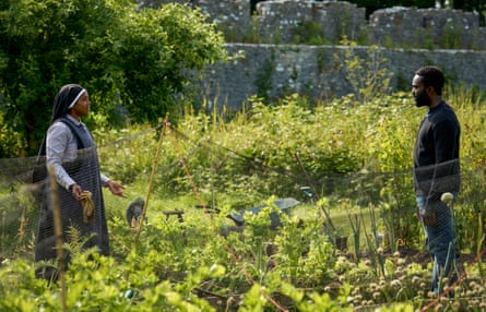 A nun in a field and a man standing opposite her on the other side of the net
