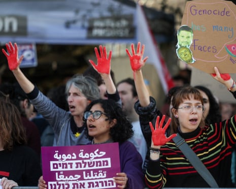 Demonstrators raise their hands covered in red paint