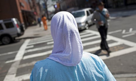 woman in a hijab pictured from behind crossing a street