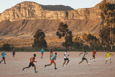 People playing soccer with rocky hills as a backdrop.