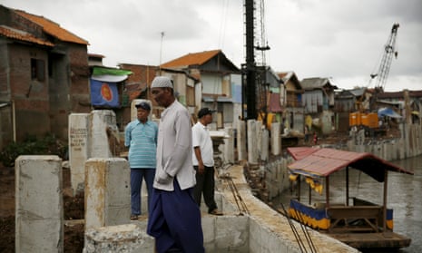 Residents walk on a concrete floodwall by Ciliwung river in Jakarta