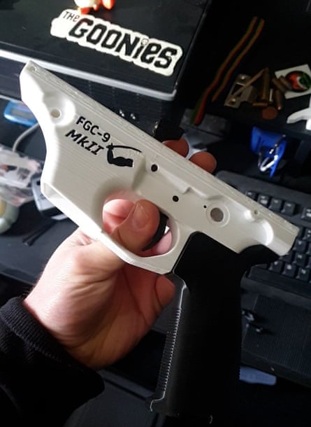 A plastic firearm held up in front of a computer keyboard and box with a Goonies sticker