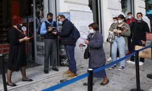 A shop worker checks customers’ Covid vaccination certificates today in Athens as the Greek government imposed further measures for unvaccinated citizens.