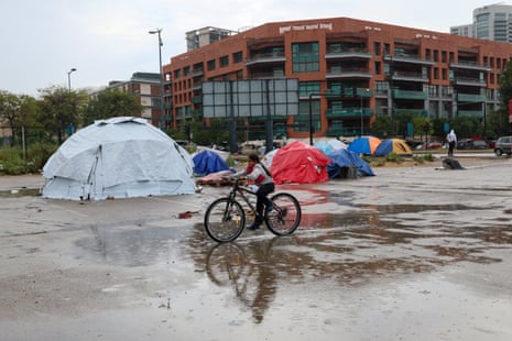 A displaced girl rides a bicycle on a rainy day at a makeshift camp for displaced people in Beirut.