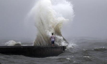 A wave crashes as a man stands on a jetty near Orleans Harbor in Lake Pontchartrain.