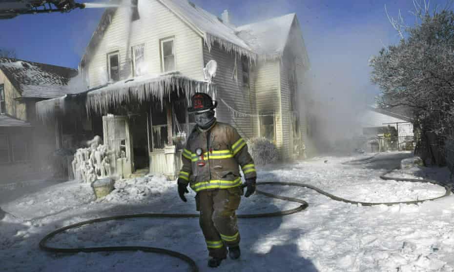 A firefighter, his clothing frozen from the extreme cold, walks by an early morning house fire in St. Paul, Minnesota.