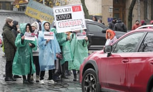 Demonstrators hold posters reading “Say No to genocide” as they try to block a street during an anti-vaccination protest in Kyiv, Ukraine.