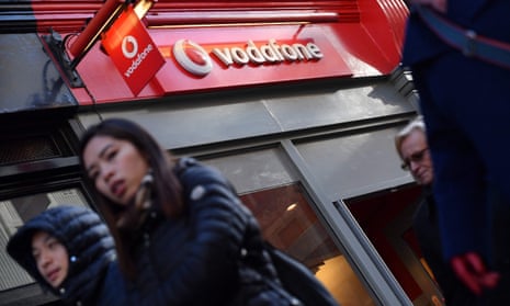 People walk past a Vodafone store in London