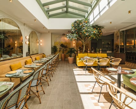 A hotel dining room with yellow bench seats and a skylight.