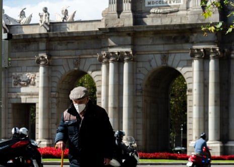 A man wearing a face mask in front of the Puerta de Alcalá, Madrid.
