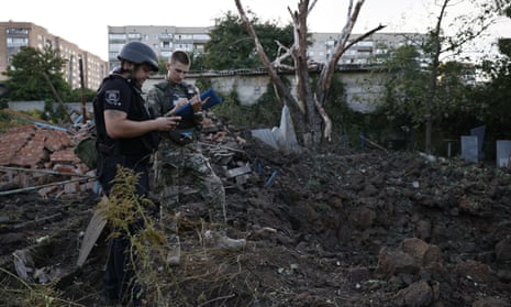 A Ukrainian soldier and a police officer near a hole left by a missile strike in the local cemetery in Kramatorsk on Saturday