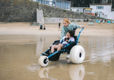 Beau Walters pushes her brother Brody down to the water’s edge in a beach-adapted wheelchair.