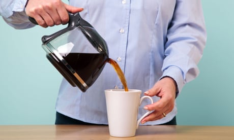 Photo of a woman on her break pouring herself a mug of hot filtered coffee from a glass pot.