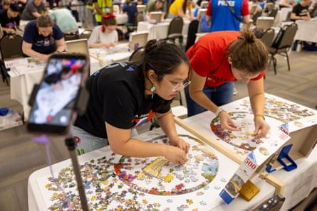 A phone on a monopod recording two people working on a round puzzle