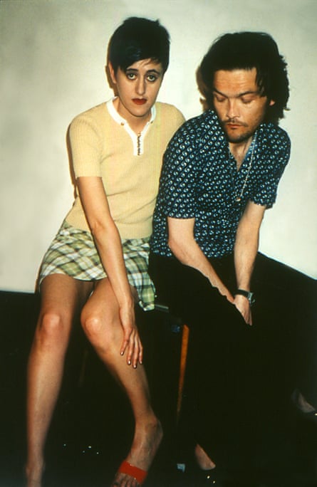 Tracey Thorn wearing a yellow top and a short green tartan shirt. Ben Watt is wearing a blue shirt and black trousers.