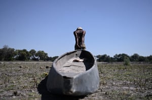 A poller drags a traditional boat across a dried channel near the village of Nxaraga in the Okavango Delta