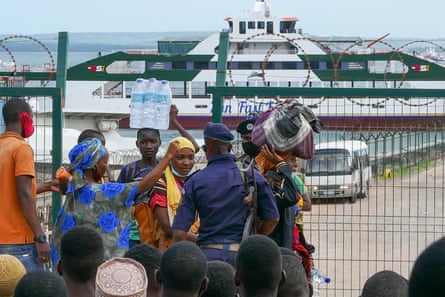 Displaced people stand near a fence at a port