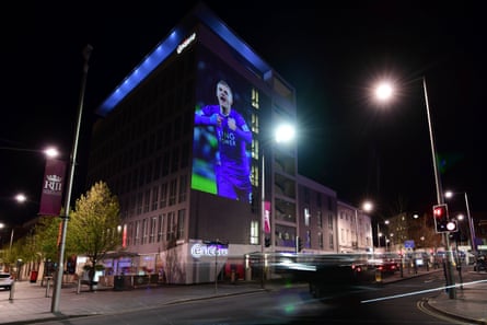 A large projection of Leicester striker Jamie Vardy is seen on the side of a building.
