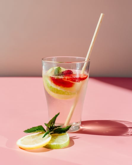 Glass cup of fresh strawberry lemonade with zero waste bamboo straw on sunny summer day on pink tabletop