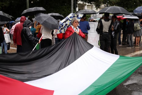 A pro-Palestinian demonstrator holds a Palestinian flag as they protest outside the Ministry of Foreign Affairs in Athens, Greece.