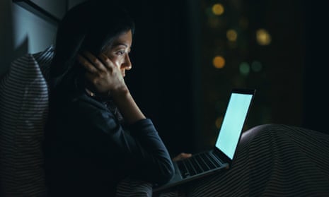 Young woman in deep thought while using laptop on bed at night