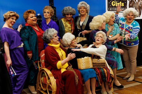 Eleven people cosplaying as the Golden Girls laugh and mug for the camera
