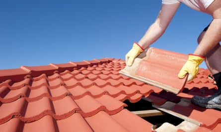 Worker with yellow gloves replacing red tiles on house