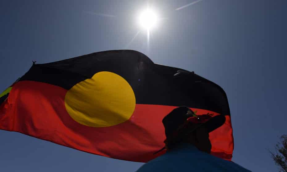 A man is seen under the Aboriginal flag