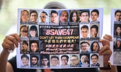 A supporter holds a poster showing some of the 47 activists on trial at the West Kowloon court