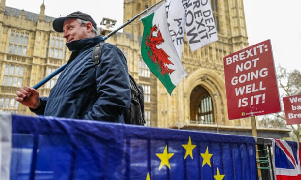 A pro-leave demonstrator walks past pro-remain placards opposite the Houses of Parliament on 3 April 2019. 