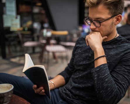 A young man reading a book in a cafe