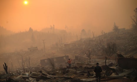 People walk amid the remains of burnt down buildings after a forest fire in Santa Olga on 26 January. The impoverished village is surrounded by hugely profitable plantations.