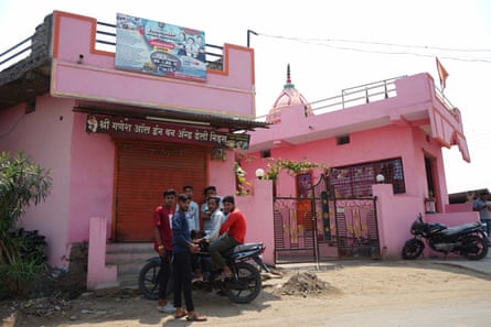 A group of young men pose for a photo in front of a bright pink building