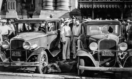 black and white photo of old cars and people around them