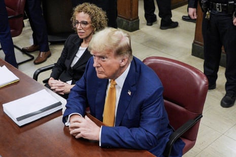 a man in a blue suit and yellow tie sits in court