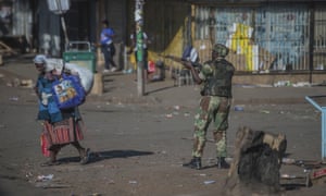An armed soldier patrols a street in Harare during protests.