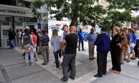 People stand in a queue to use ATM machines at a bank in Thessaloniki on June 27, 2015.
