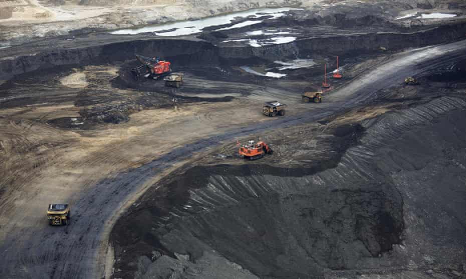 Heavy earth moving machinery move raw tars sands at the Syncrude tar sands mining operations near Fort McMurray, Alberta.