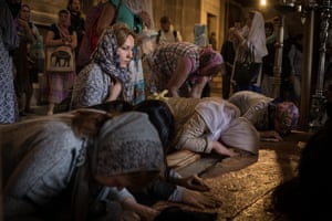 Women in headscarves kneeling and bending their heads