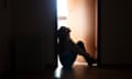 A teenage girl sitting in a dark doorway with light coming from an adjoining room