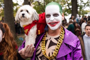 An owner dressed as The Joker, with a dog dressed as Wonder Woman.