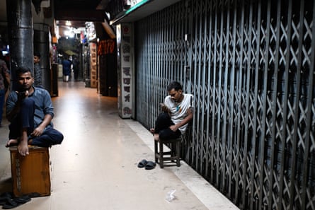 Two men sit outside closed shops