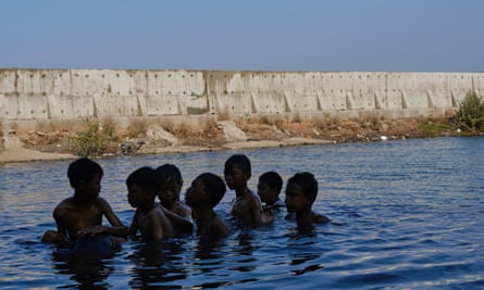 Boys swim in floodwater on the land side of a recently built seawall in Jakarta, Indonesia.