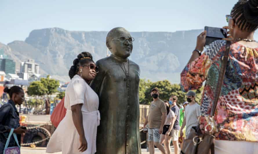 A woman poses for a photograph by South African anti-apartheid icon Archbishop Desmond Tutu’s statue on the wake of his death