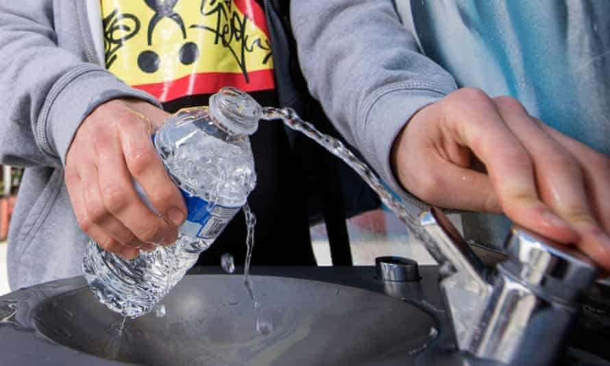 Students refilling a water bottle at a fountain.