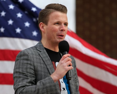 Ryan Fournier speaking into a microphone in front of a US flag