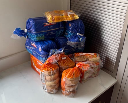 Several bags of bread, bagels, crumpets and rolls piled on a worktop