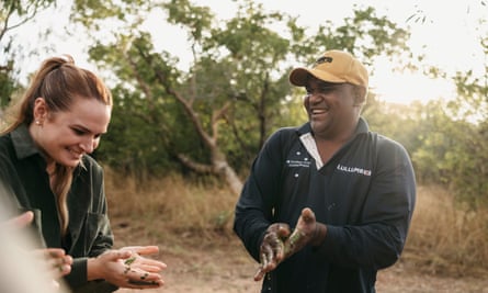 Image of a man and woman smiling in bushland, as the man explains something using his hands.