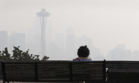 Bir kadın Kerry Park'ta bir bankta oturuyor ve Seattle silüetine bakıyor.